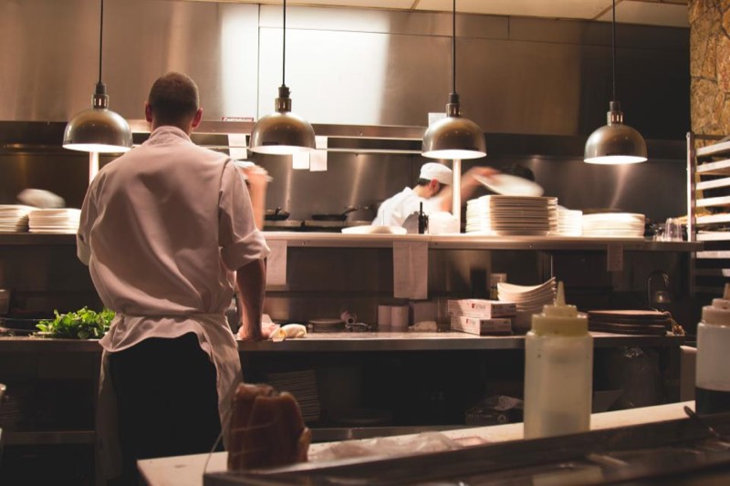Chefs working a busy restaurant line under heat lamps, where extract and make up air matter as much as cooling